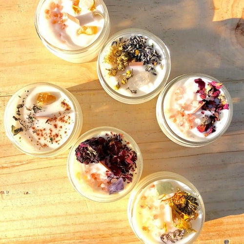 "🕯️ Bougie d'intention artisanale bio en cire de soja naturelle avec flamme douce brûlant paisiblement, entourée de lavande séchée, cristaux de quartz rose et sauge sur surface bois naturel créant ambiance zen méditation purification spirituelle ✨🌿"